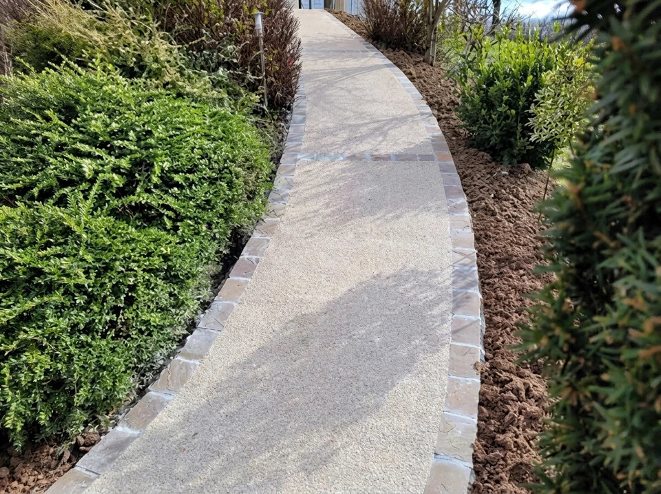 Allée d'entrée privée bordée d'arbres matures, portail ouvert avec piliers en pierre naturelle et ferronnerie noire