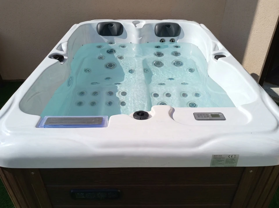 Scène nocturne d'un spa extérieur avec piscine illuminée en bleu et fontaine