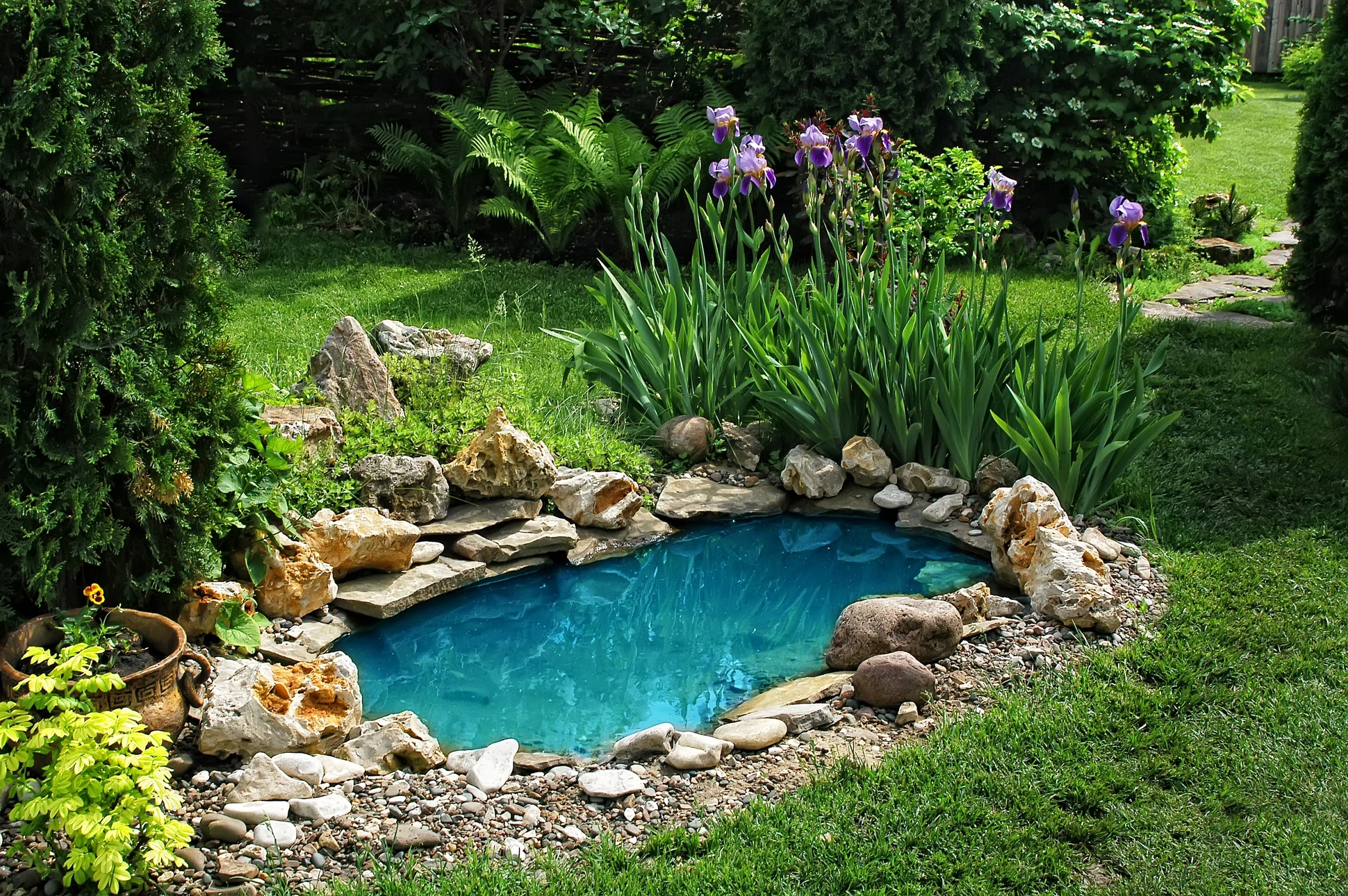 Jardin extérieur aménagé avec bacs de plantation surélevés en bois, contenant diverses plantes fleuries roses, lavande violette et feuillages verts
